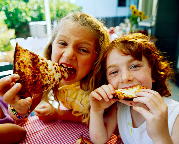 girls eating pizza - junk food stock pictures, royalty-free photos & images