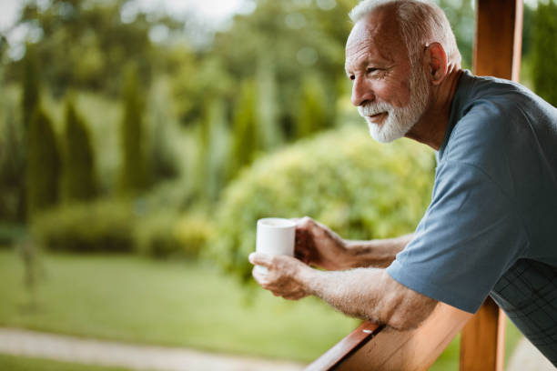 glimlachend volwassen man genieten in de ochtend koffie op een terras. - coffee stockfoto's en -beelden