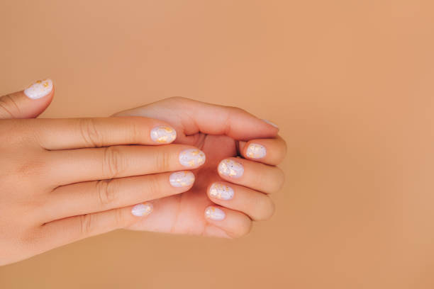 glowing hands with nude color manicure with gold particles on beige background. trendy colors of the year - nails art stock pictures, royalty-free photos & images