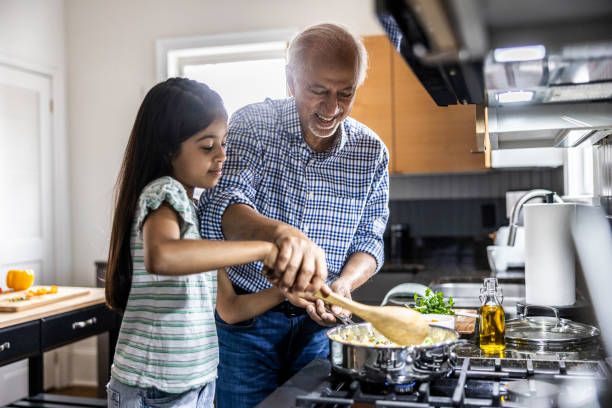 grandfather and granddaughter cooking in kitchen - food stock pictures, royalty-free photos & images