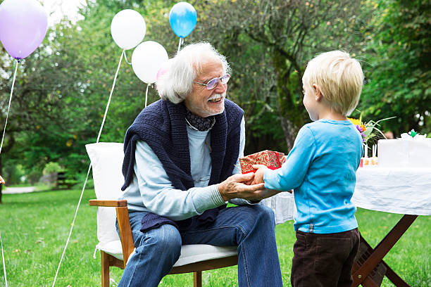 grandfather receiving gifts on birthday party in garden - garden decoration stock pictures, royalty-free photos & images