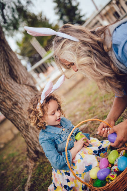 grandmother and granddaughter with easter eggs basket in garden - garden decoration stock pictures, royalty-free photos & images