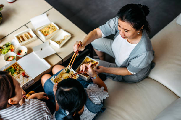 grandmother feed her granddaughter with chinese food - junk food stock pictures, royalty-free photos & images
