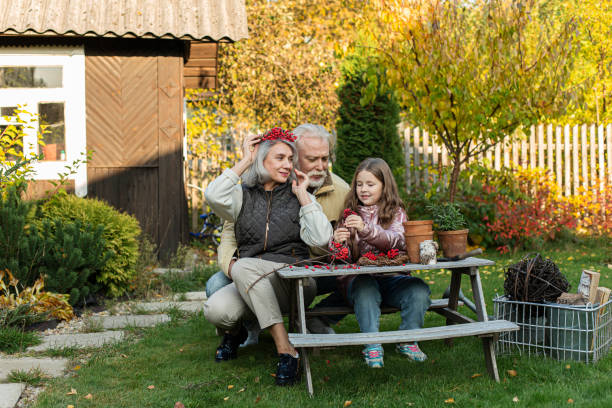grandparents and granddaughter sitting at garden table crafting with mountain ash - garden decoration stock pictures, royalty-free photos & images
