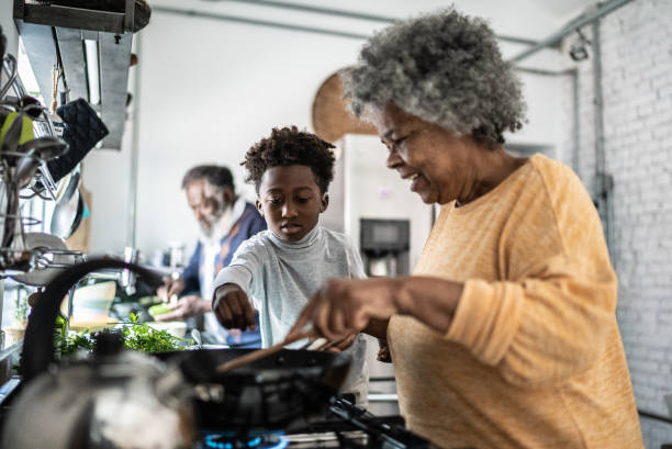 grandson helping his grandmother cooking at home - food stock pictures, royalty-free photos & images