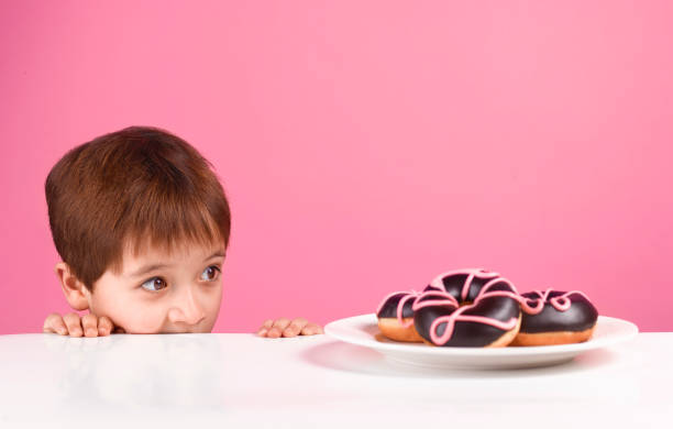greedy boy looking at doughnuts - junk food stock pictures, royalty-free photos & images