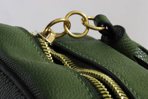 green handbag with unzipped gold colored zipper with three metal rings attached - fashion stock pictures, royalty-free photos & images