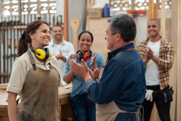 group of carpenters congratulating an apprentice and clapping - home decoration stock pictures, royalty-free photos & images