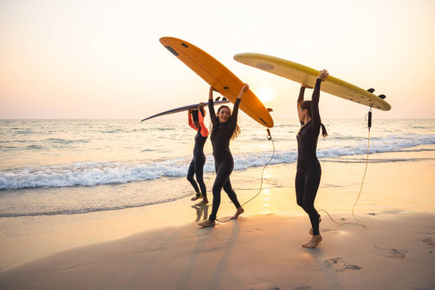 group of female surfers walking on the beach - travel stock-fotos und bilder
