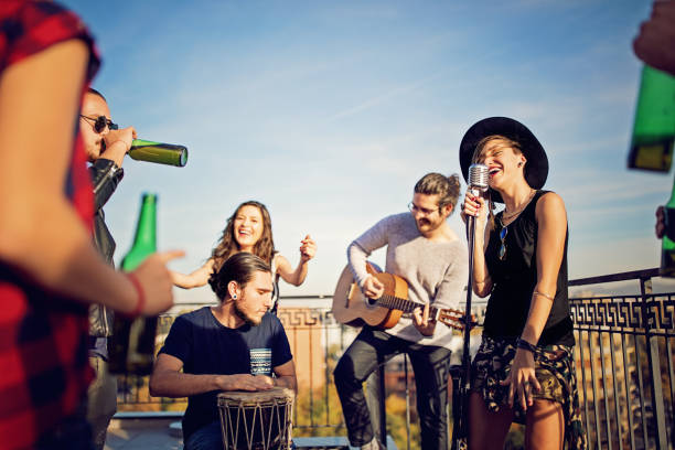 group of friends are celebrating with a concert on the roof terrace - concert stock pictures, royalty-free photos & images