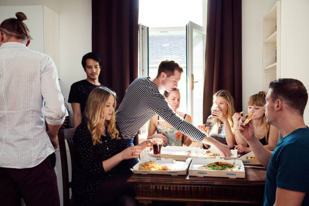 group of friends chatting over drinks and pizza at home - junk food stock pictures, royalty-free photos & images