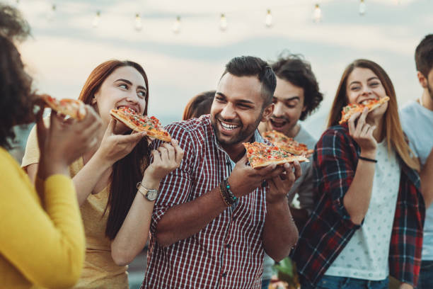 group of friends eating pizza - junk food stock pictures, royalty-free photos & images