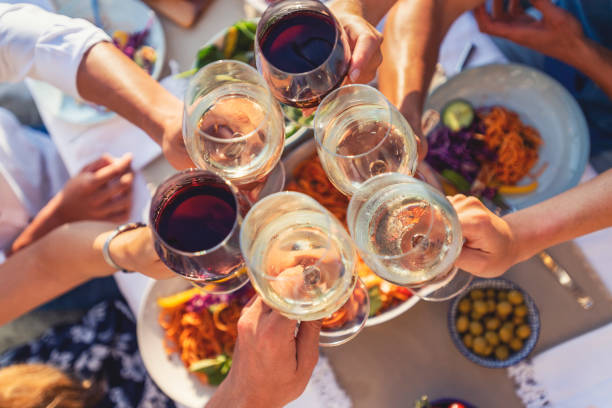 group of friends having a meal outdoors. they are celebrating with a toast using wine - food stock pictures, royalty-free photos & images