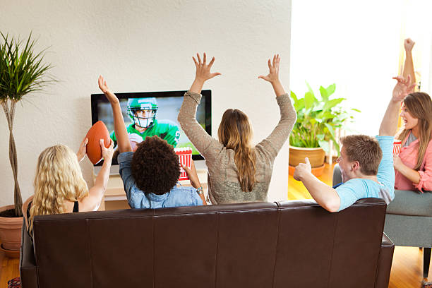 group of friends watching and cheering football game together - home decoration stock pictures, royalty-free photos & images