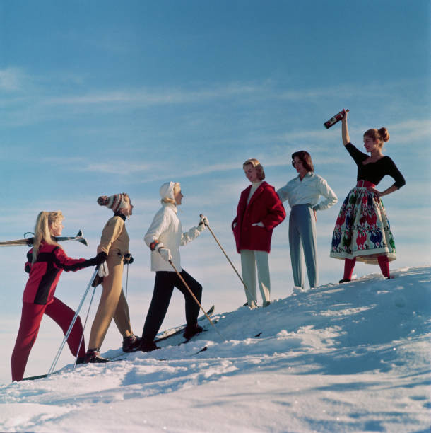 Group of ladies welcome their friends back from a day's skiing, with an apres ski drink.