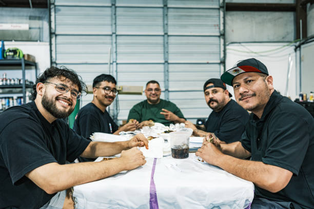 group of latino males having lunch at auto body paint shop - junk food stock pictures, royalty-free photos & images