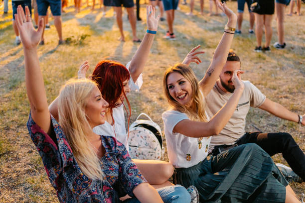 group of people sitting on a grass and dancing at the music festival - concert stock pictures, royalty-free photos & images