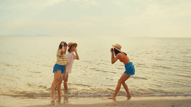 group of young asian women taking photo picture by retro vintage camera on tropical beach. - concert stock pictures, royalty-free photos & images