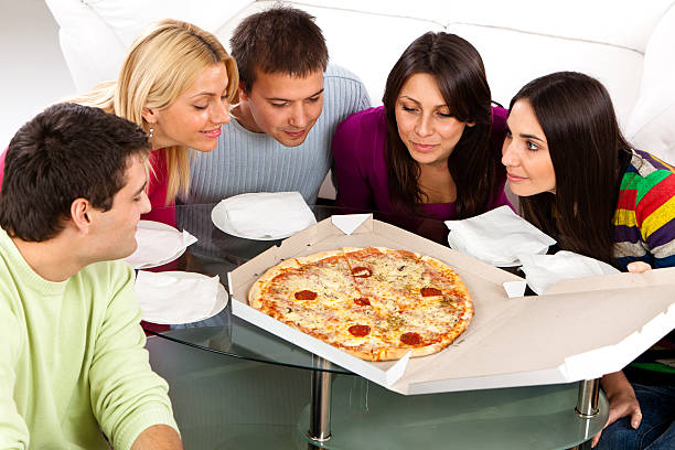 group of young students preparing to eat pizza - junk food stock pictures, royalty-free photos & images