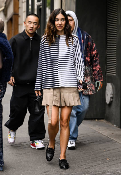 Guest is seen wearing a black and white striped shirt, tan skirt and black shoes sunglasses outside the Sacai show during Womenswear Spring/Summer...