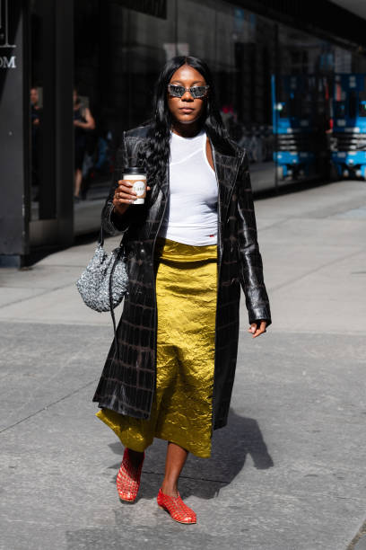 Guest is seen wearing a black coat, white top, green skirt, red mesh shoes, silver sunglasses and carrying a silver bag outside the Carolina Herrera...