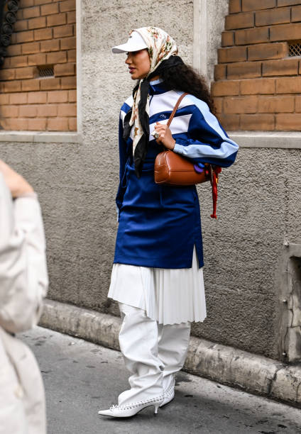 Guest is seen wearing a blue and white Lacoste jacket, white panel skirt white pants and white boots with Lacoste brown bag and white had and...
