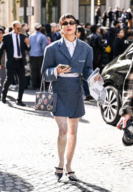 Guest is seen wearing a blue Miu Miu jacket and skirt, Miu Miu bag, laced leggings and black shoes outside the Lacoste show during Womenswear...