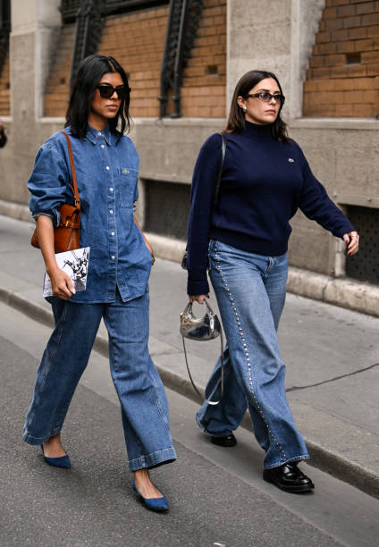 Guest is seen wearing a denim Lacoste shirt and jeans, blue shoes, black sunglasses and brown bag with a guest wearing a blue Lacoste sweater, blue...