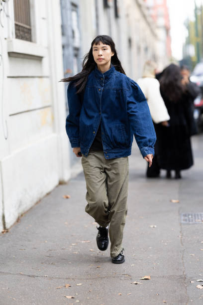 Guest is seen wearing a denim puffy bomber jacket, a black shirt, black leather loafers and military green trousers outside Marni show during the...