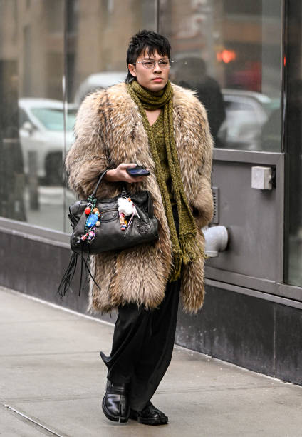 Guest is seen wearing a faux fur tan coat, black bag, black pants, black shoes and green scarf outside the Christian Siriano show during NYFW F/W...