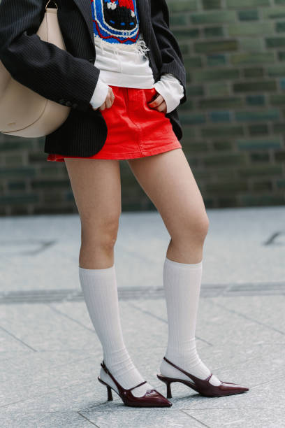 Guest is seen wearing a jacket, top, red mini skirt, long white socks, dark red shoes during Rakuten Tokyo Fashion Week A/W 2025 on March 22, 2025 in...