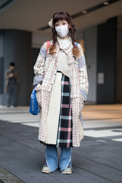 Guest is seen wearing a patchwork plaid coat, plaid skirt and torn blue jeans during the Amazon Fashion Week TOKYO 2018 A/W on March 22, 2018 in...