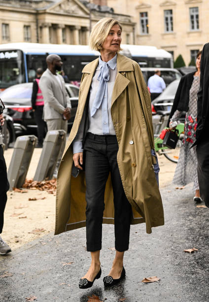 Guest is seen wearing a tan trench coat, blue blouse, black jeans and black outside the Chanel show during the Womenswear Spring/Summer 2024 as part...