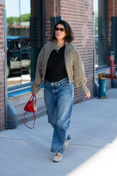 Guest is seen wearing printed black and brown jacket, black top, blue denim pant, cream shoes, brown sunglasses and carrying a red bag outside the...