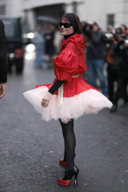Guest seen wearing a red long coat with white puffy details, black tights, black sunglasses, black hairband and black turtleneck and black and red...