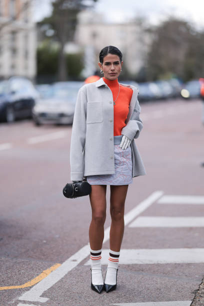 Guest seen wearing orange turtleneck, creme jacket, light rose skirt, white socks, black heels and a Lacoste leather bag outside Lacoste Show during...