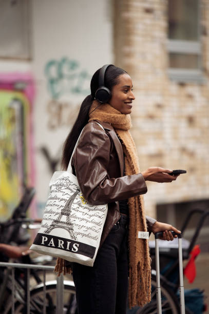 Guest wearing a brown leather jacket, brown long scarf, and black headphones outside Aeron during the Copenhagen Fashion Week Autumn/Winter 2023 on...