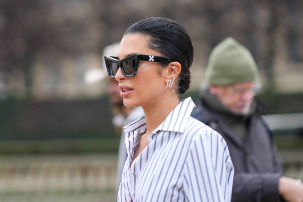Guest wears a black and white striped shirt, Off-White sunglasses, earrings, outside Off-White, during the Womenswear Fall/Winter 2024/2025 as part...