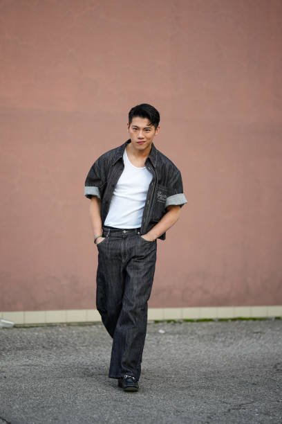 Guest wears a black Gucci denim opened jacket with cuffed short sleeves, a white t-shirt, black denim flared pants, black leather pointed shoes,...