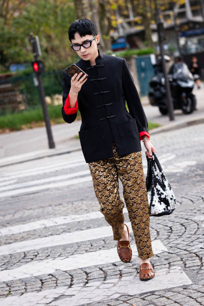 Guest wears a black jacket gold printed pants black sequins dress, outside Courreges, during the Womenswear Spring/Summer 2024 as part of Paris...