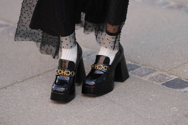 Guest wears a black polka dots print pattern tulle long skirt, white socks, black shiny varnished leather block heels / platform loafers, outside...