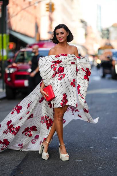 Guest wears a bridal face veil, a red and white off-shoulder floral print pattern midi on-knee and long dress with printed polka dots, white platform...