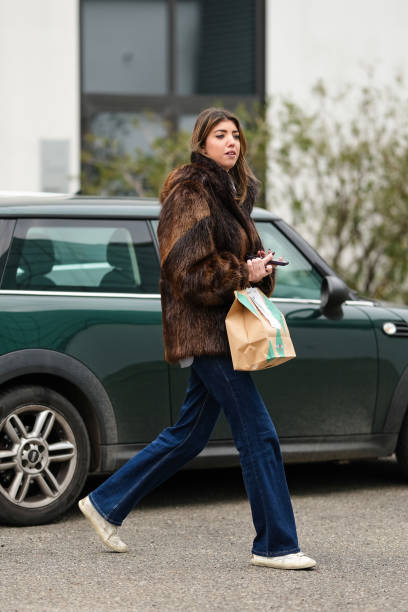 Guest wears a brown faux fur fluffy jacket, dark blue denim jeans : pants, white leather sneakers shoes, outside Jordanluca, during the Milan Fashion...