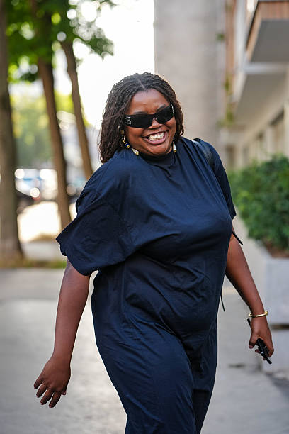 Guest wears a dark navy, short-sleeved dress with a relaxed fit. The dress appears to be made of a lightweight fabric. Sunglasses from Balenciaga...