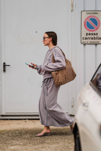 Guest wears a gray wool jacket, brown leather Gucci bag, long gray wool skirt, gray kitten heels, outside Jil Sander, during the Milan Fashion Week...
