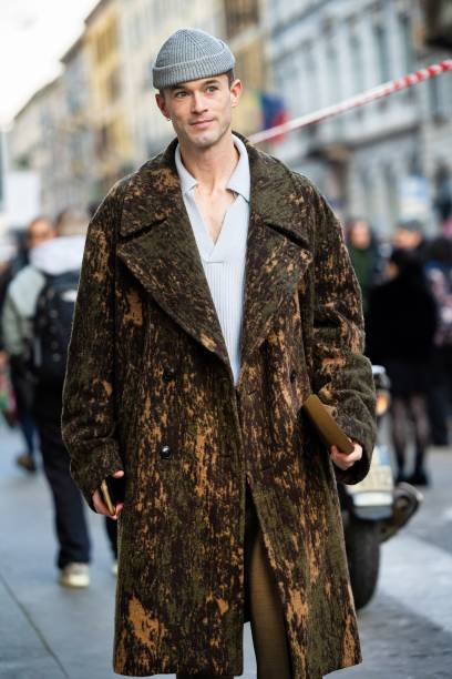 Guest wears a grey hat, a white shirt, military green trouser and a green and beige knitted long coat outside Pierre-Louis Mascia show during the...