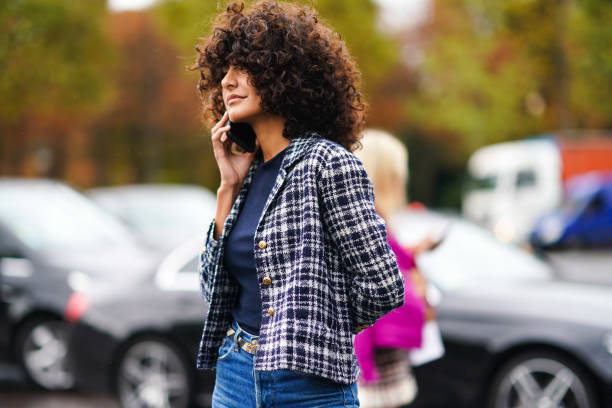 Guest wears a navy blue top, a black and white checkered Chanel jacket, blue denim pants, outside Chanel, during Paris Fashion Week - Womenswear...