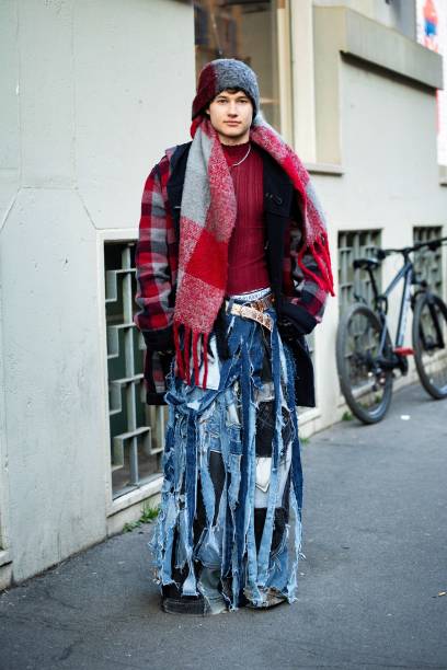 Guest wears a red and grey checked knitted maxi scarf, a red sweater, a red, black and grey checked coat, a white belt and denim ripped wide leg...