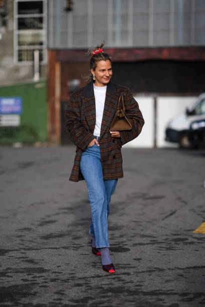 Guest wears a red hair scrunchie, earrings, a white t-shirt, a brown checkered / checked pattern printed oversized blazer jacket, a brown leather...