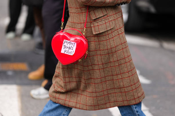 Guest wears a red heart-shaped bag with the written inscription "Protect Trans Kids", outside Altuzarra, during New York Fashion Week, on February...
